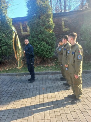 Na zdjęciu policjant ze sztandarem i uczniowie szkoły.