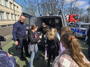 Na zdjęciu policjant oraz dzieci wchodzące do radiowozu