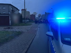 Na zdjęciu policyjny radiowóz, w tle procesja drogi krzyżowej