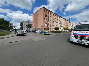 Na zdjęciu widać dwa bloki, ulicę, radiowóz,karetkę pogotowia,  samochody oraz uczestników biegu.