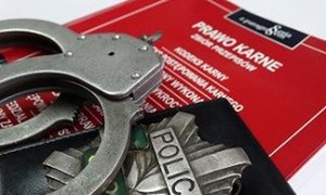 Grafika przedstawia kajdanki i:blachę&quot; policyjną ułożone na kodeksie w czerwonej okładce