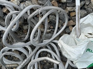 Na zdjęciu srebrne kable i brzeszczot w plastikowej torbie ułożonej na kamieniach.