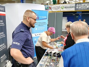 Na zdjęciu policjant przy stoisku Komendy Miejskiej Policji w Chorzowie oraz dwie kobiety i mężczyzna