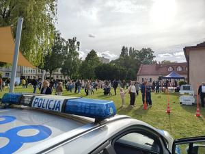 Na zdjęciu fragment radiowozu oraz ludzie obecni na festynie