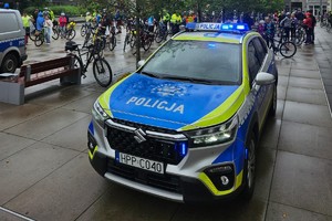 Na zdjęciu radiowóz a za nim tłum ludzi na rowerach