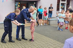 Na zdjęciu policjanci wręczający dzieciom medale