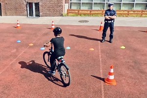 Na zdjęciu policjant i chłopiec na rowerze zdający egzamin na kartę rowerową