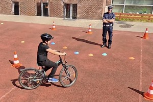 Na zdjęciu policjant i chłopiec na rowerze zdający egzamin na kartę rowerową