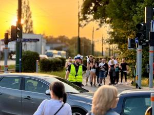 na fotografii widoczny jest funkcjonariusz kierujący ruchem drogowym stojący w tłumie pieszych