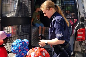 Na zdjęciu policjanta z dziećmi przy radiowozie