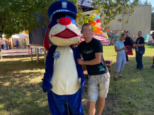 Na zdjęciu ,mężczyzna i maskotka Sznupek stojący obok siebie