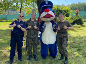 Na zdjęciu dwie dziewczyny, policjantka i maskotka Sznupek stojący obok siebie
