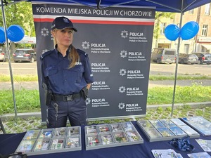Na zdjęciu policjantka stojąca za stołem z materiałami promocyjnymi Policji