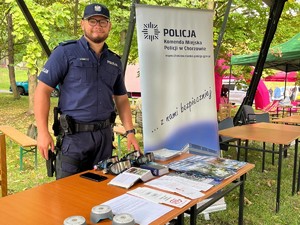 Na zdjęciu policjant przy stosiku profilaktycznym a za nim baner Komendy Miejskiej Policji w Chorzowie